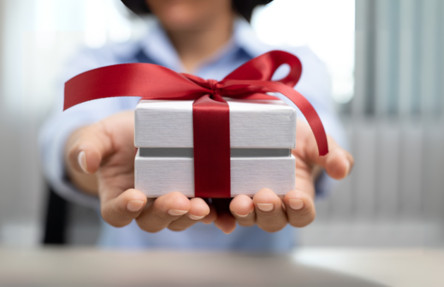 A physical therapist handing a wrapped gift to a patient in a clinic setting, symbolizing thoughtful Christmas gift ideas for therapy practices.