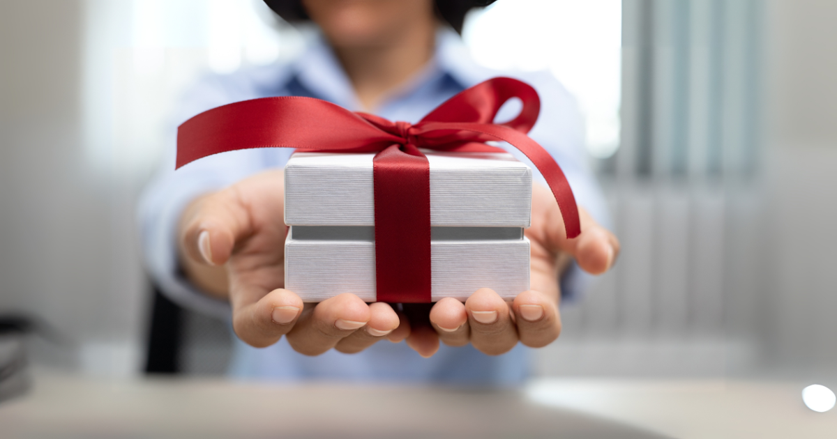 A physical therapist handing a wrapped gift to a patient in a clinic setting, symbolizing thoughtful Christmas gift ideas for therapy practices.