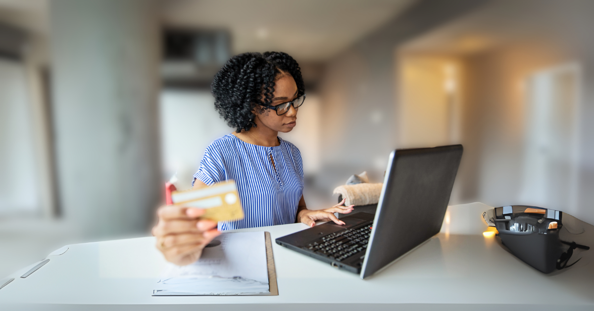 A therapist in a clinic setting reviews payment tracking and billing reconciliation data on a computer while holding a credit card, symbolizing financial management in healthcare