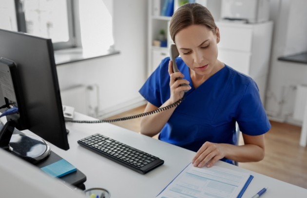 Therapist working on a computer, evaluating payment options between insurance and cash-based methods for a patient.