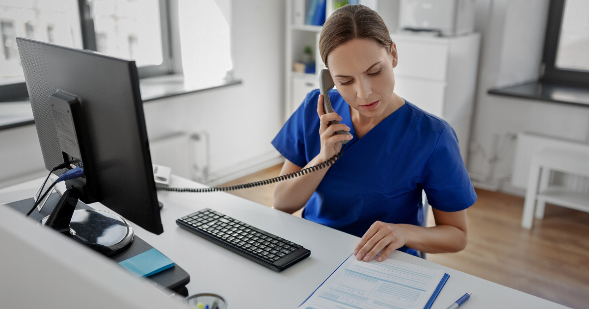 Therapist working on a computer, evaluating payment options between insurance and cash-based methods for a patient.