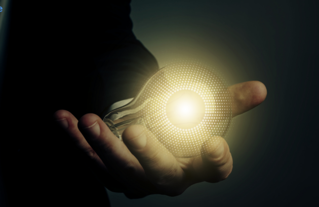 A hand holding a glowing lightbulb, symbolizing creative ideas and innovation for growth in therapy clinics. The background is dark, highlighting the importance of new strategies for clinic expansion and success.